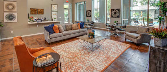 A living room with a grey couch, orange chairs, and a patterned rug.