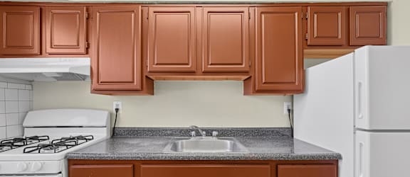 A kitchen with brown cabinets and a white refrigerator.