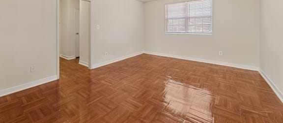 A room with a wooden floor and a window with blinds.