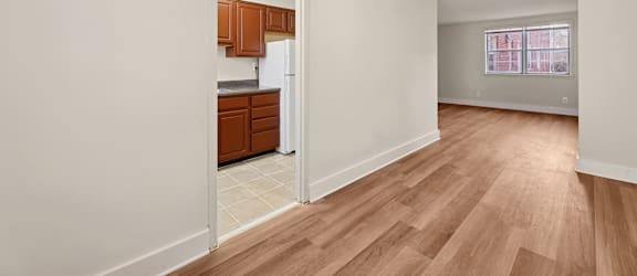 A kitchen with wooden cabinets and a refrigerator is visible through an open door.