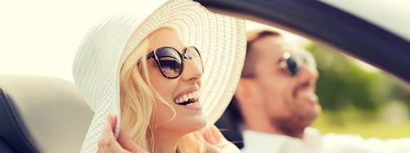 A woman in a white hat and sunglasses is sitting in a car with a man.