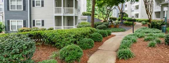 A pathway leads through a landscaped area in front of apartment buildings.