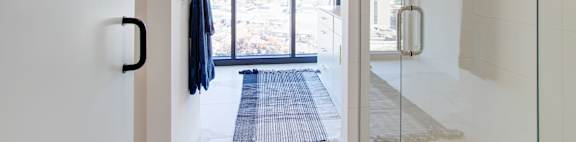 a bathroom with a glass shower and a blue rug