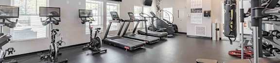 A gym with a variety of exercise equipment including treadmills, stationary bikes, and weight machines.