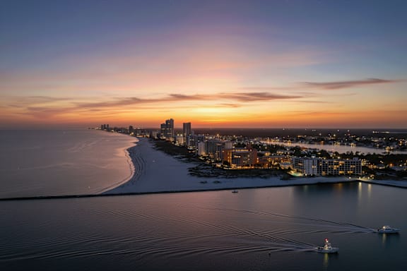 A beautiful sunset over a coastal city with boats in the water.