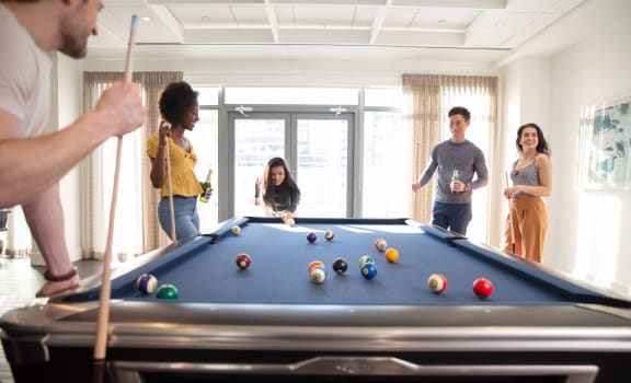a group of people are gathered around a pool table