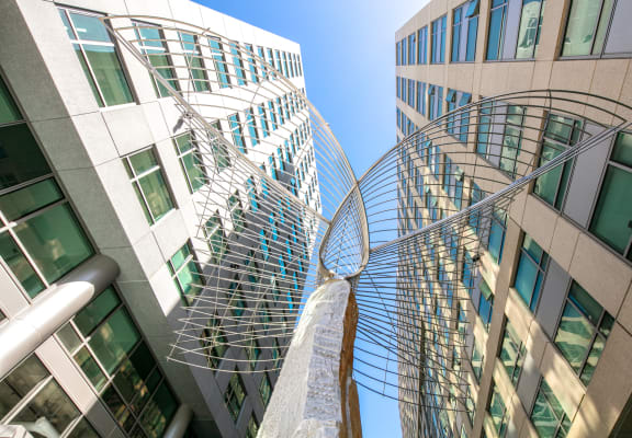 a large metal sculpture in the middle of two tall buildings