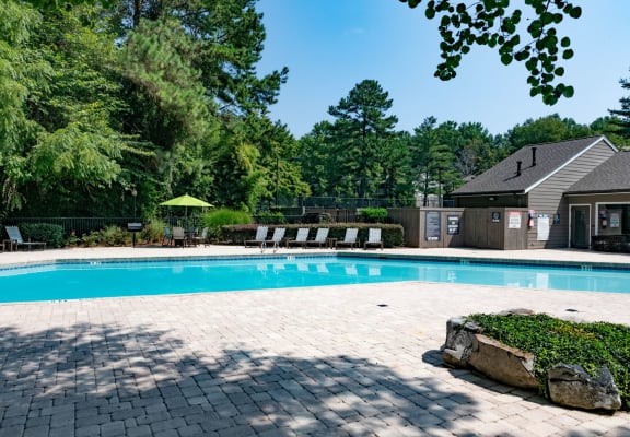 a swimming pool with a house and trees in the background