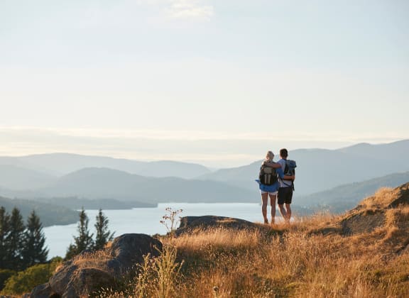 a couple standing on a hill overlooking a lake