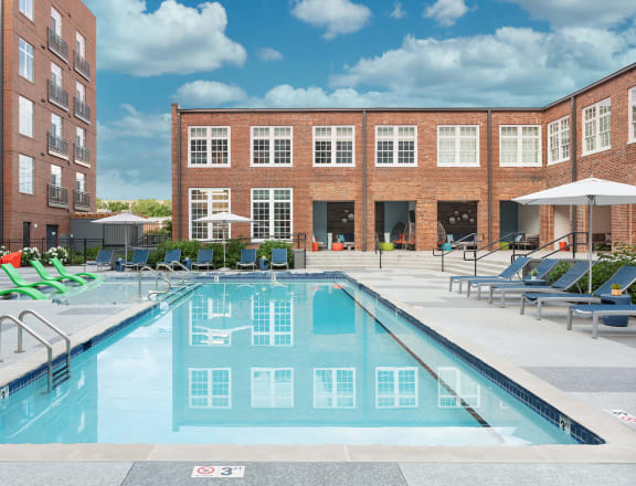 a swimming pool with lounge chairs in front of a building