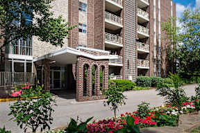 A large brick building with balconies and a walkway in front.