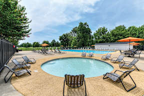 A pool surrounded by chairs and umbrellas with trees in the background. at Park at Forest Hill Apartments, Memphis