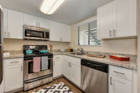 Kitchen with Granite Counters, Dishwasher, Oven, Microwave, Black/White Rug and White Cabinents