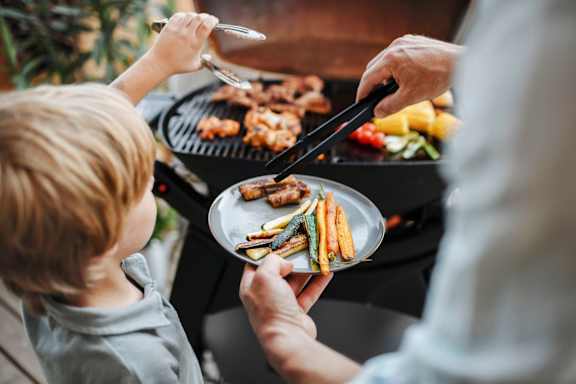 A person is grilling food for a child.
