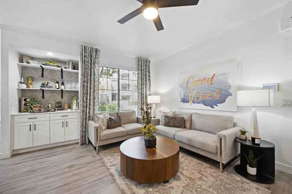A living room with a grey couch, a wooden coffee table, and a painting that says
