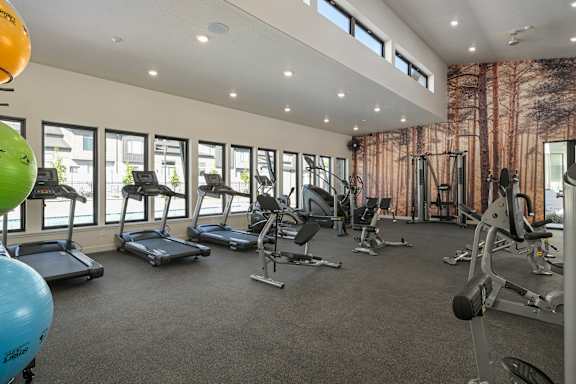 A spacious gym with treadmills, exercise bikes, and weight machines.