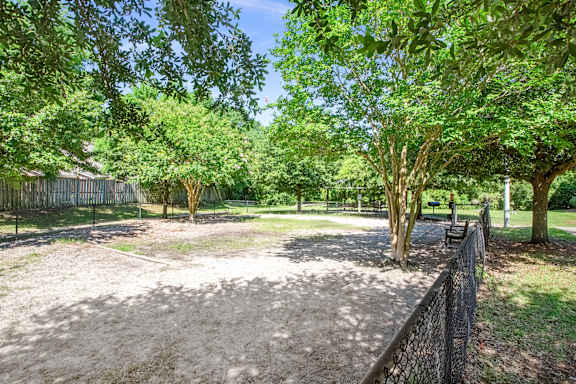 A park with a dirt area and trees.