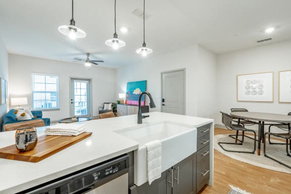 an open kitchen and living room with a white counter top and a sink