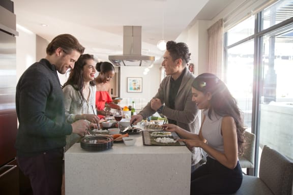 a group of people standing around a table eating food at Versus, Calgary, AB, T2R 1A8