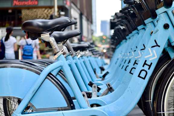 A row of blue bicycles are parked in a row.