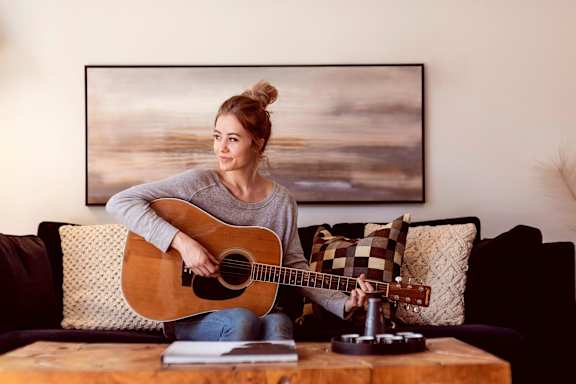 a woman sitting on a couch playing a guitar