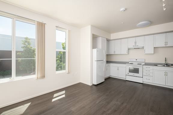 an empty kitchen with white appliances and white cabinets