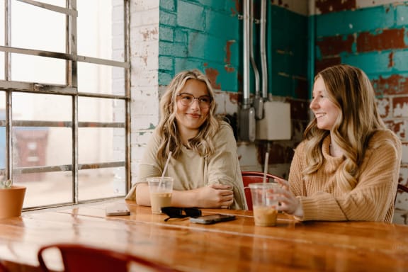 two women sitting at a table with drinks at East 4th Street, Ohio, 44115
