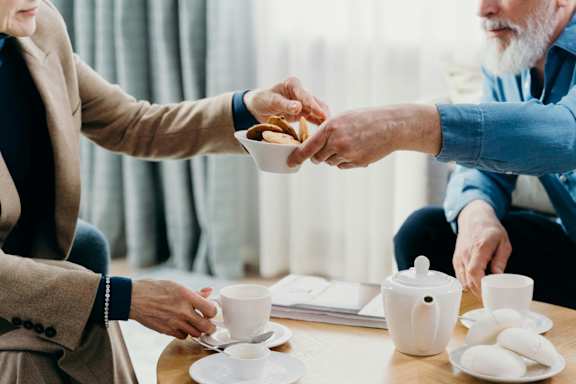 A person is serving tea to another person at a table.