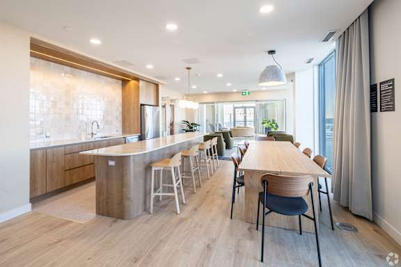 A modern kitchen with a long wooden table and chairs.