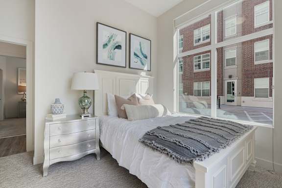 Bedroom with a large bed, a dresser, and a window overlooking a brick building at 200 City View, Provo, 84601