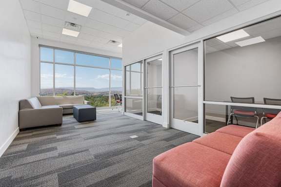 A room with a grey carpet and a large window overlooking the mountains. 605 Place Student Housing & Co-Living, St George Utah