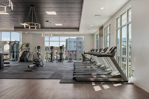 the gym with treadmills and windows at the district flats apartments 605 Place Student Housing & Co-Living, St George, UT 84770
