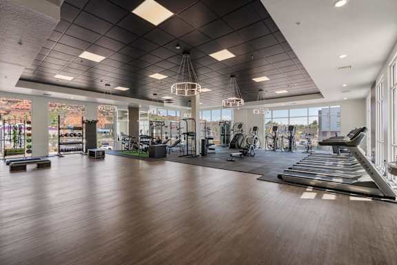 A spacious gym with a variety of equipment and a large mirror on the wall. 605 Place Student Housing & Co-Living, St George, 84770