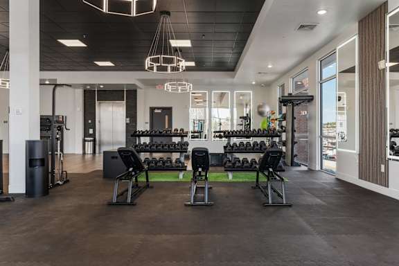 A gym with a variety of equipment including weights and cardio machines. 605 Place Student Housing & Co-Living, St George, UT 84770