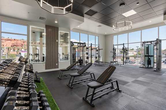 A gym with a row of benches and a row of dumbbells. 605 Place Student Housing & Co-Living, St George, 84770