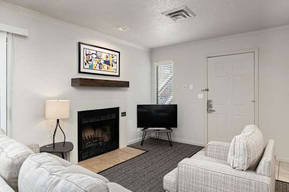A living room with a fireplace, a couch, a chair, and a painting on the wall.