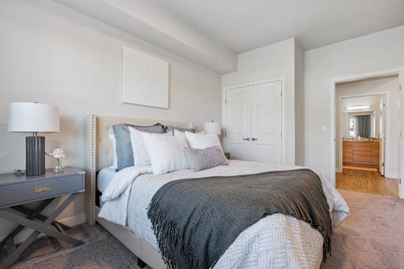 A bedroom with a large bed and a nightstand with a lamp.