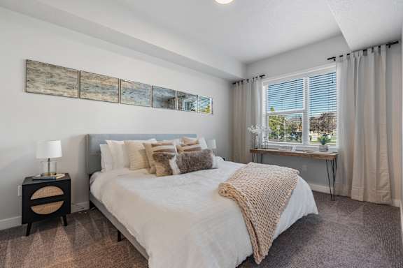 A bedroom with a large bed and a window overlooking a tree-filled landscape.