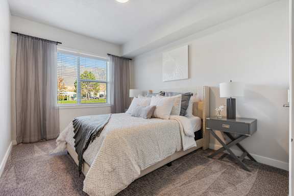 A bedroom with a large bed and a window with curtains.