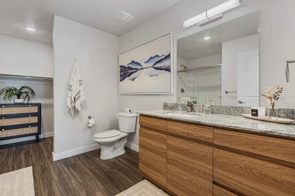 A bathroom with a toilet, sink, and a painting on the wall.