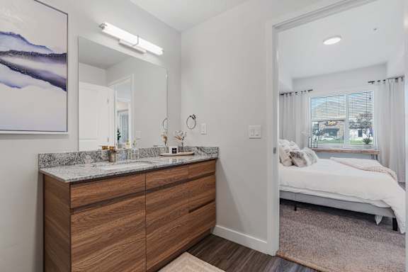A bedroom with a large bed and a wooden vanity with a mirror.