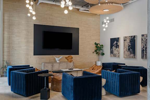 A modern living room with a large TV mounted on the wall and blue striped furniture.