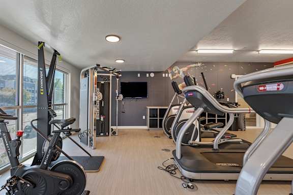 A gym with treadmills, exercise bikes and a television.