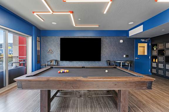 A pool table in a room with a blue wall and a television.
