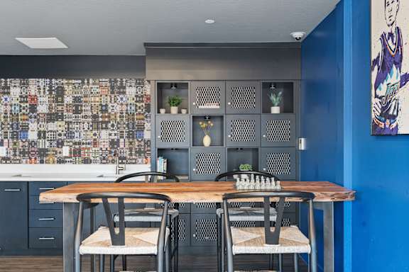 A kitchen with a table and chairs in front of a wall with a cityscape mural.