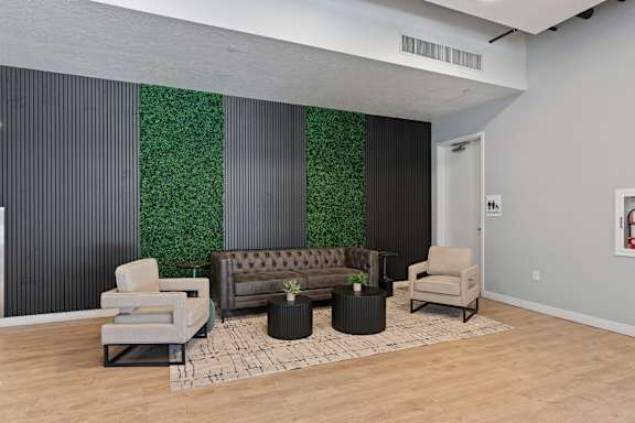 A living room with a couch, chairs, and a green wall.