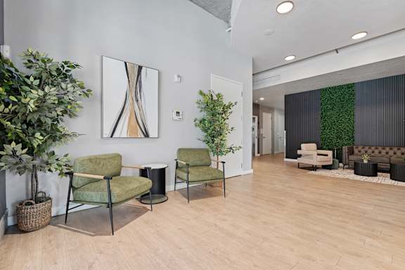 A modern living room with green chairs and a large mirror on the wall.