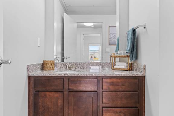 A bathroom with a brown vanity and a mirror above it.