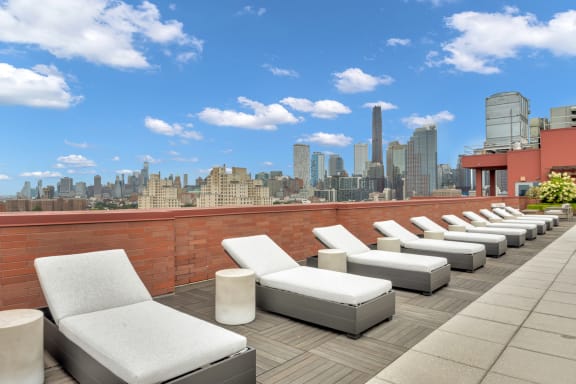 a terrace with white lounge chairs and a view of the city