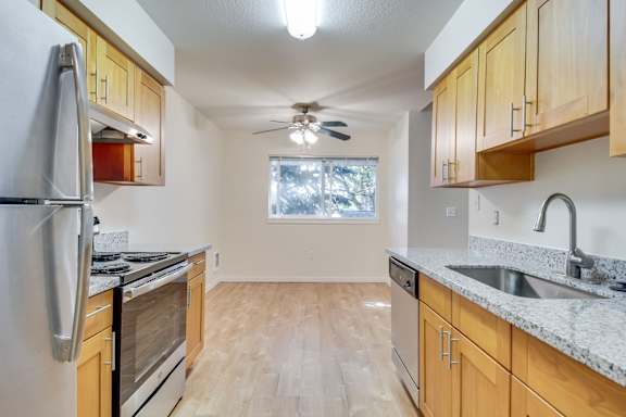 A kitchen with wooden cabinets and a stainless steel refrigerator.